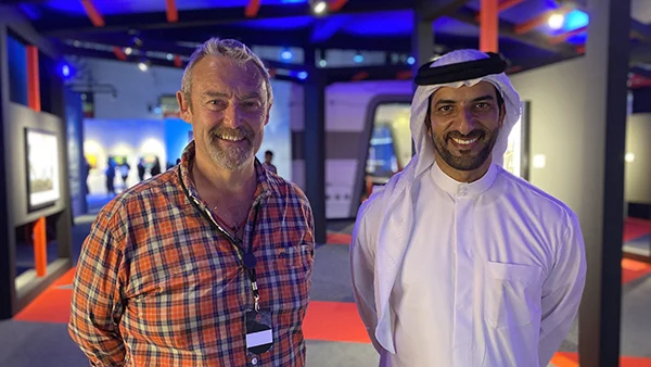 Two men one wearing red plaid shirt and the other a dishdasha at the expo centre in Sharjah UAE